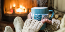 person sitting in front of fire with wool socks and a hot mug person sitting in front of fire with wool socks and a hot mug