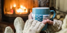 person sitting in front of fire with wool socks and a hot mug