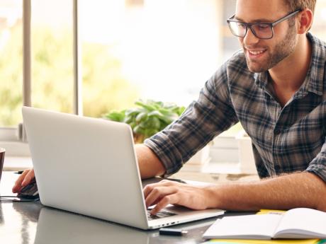 man happy at home looking at laptop