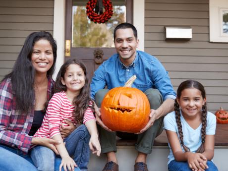 family on front porch holding a pumpkin 