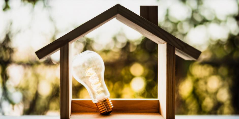 wooden hollow house with lightbulb inside with sun and leaves in background