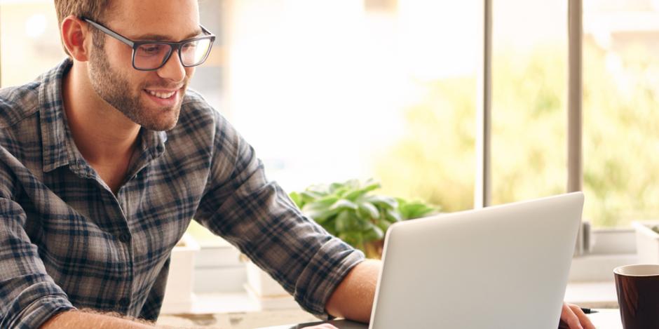 man happy at home looking at laptop