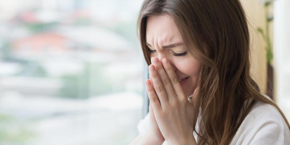 woman sneezing at home