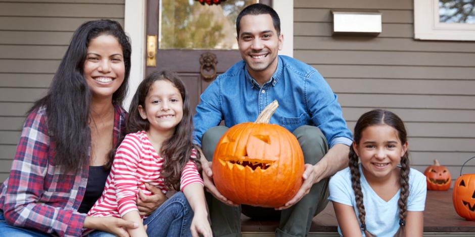 family on front porch holding a pumpkin 