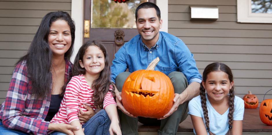 family on front porch holding a pumpkin